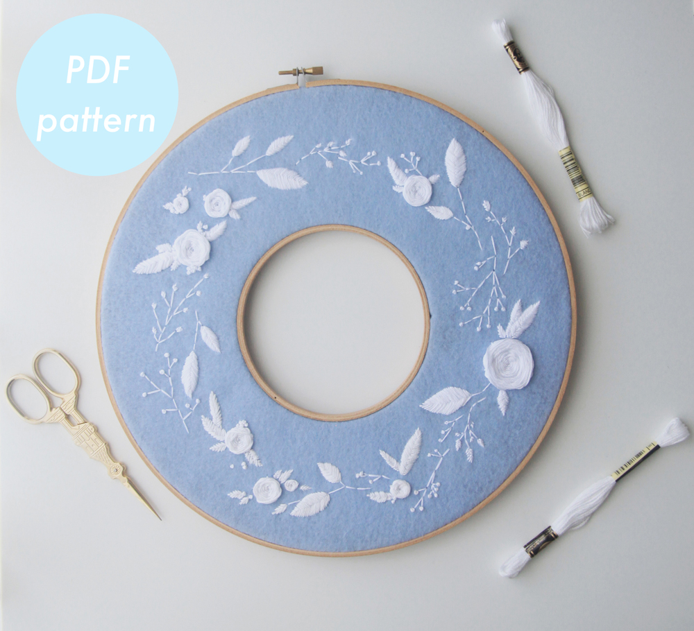 modern embroidery floral hoop wreath with white thread and blue felt background