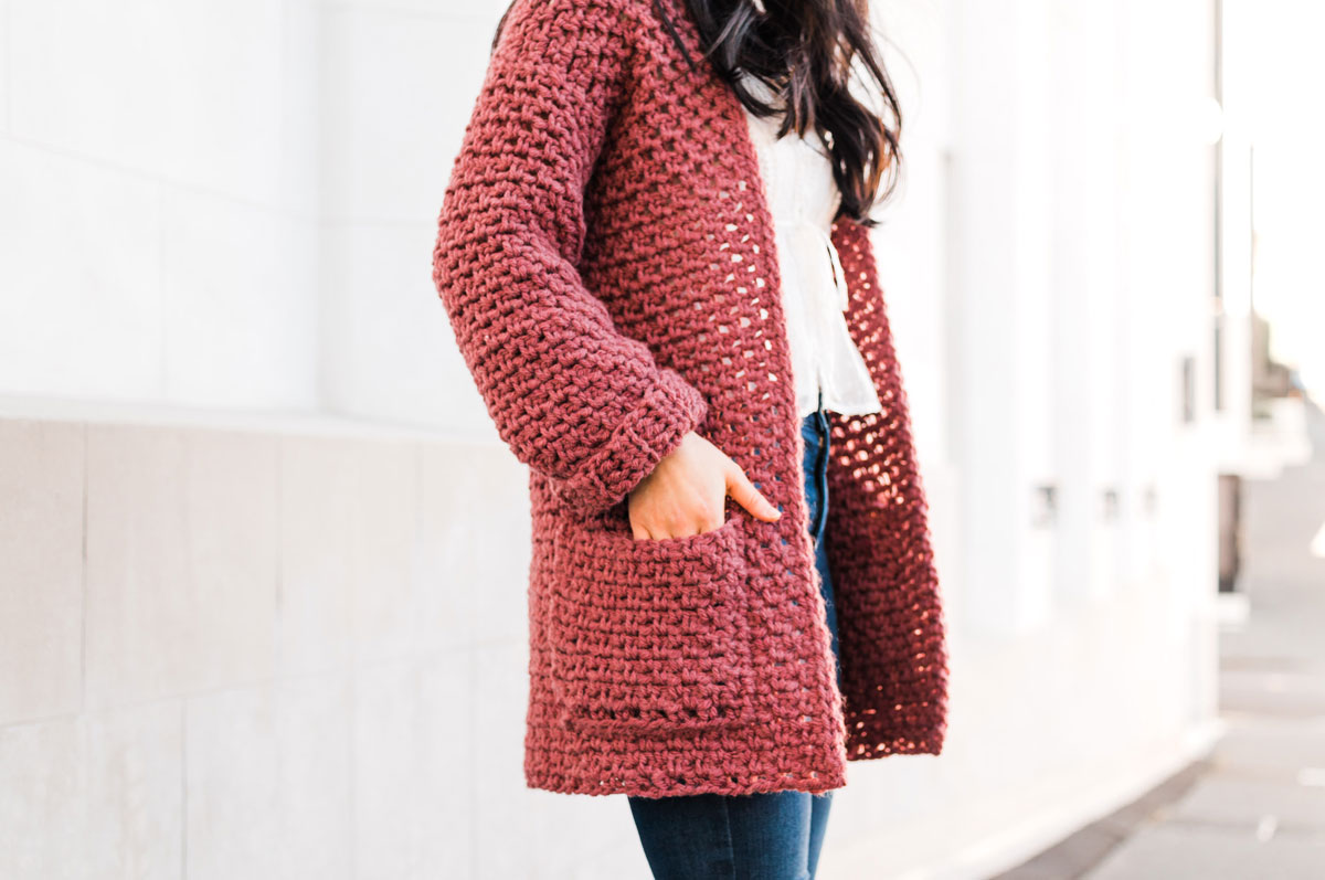close up on handmade crochet coat with model's hands in pockets