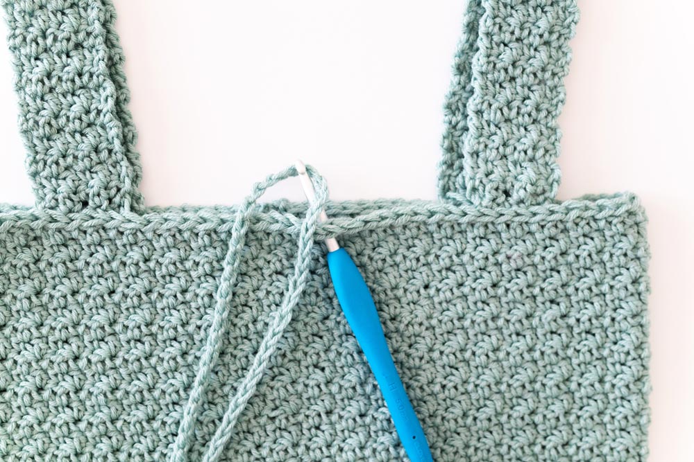 crochet hook pulling chain through neckline of crop top