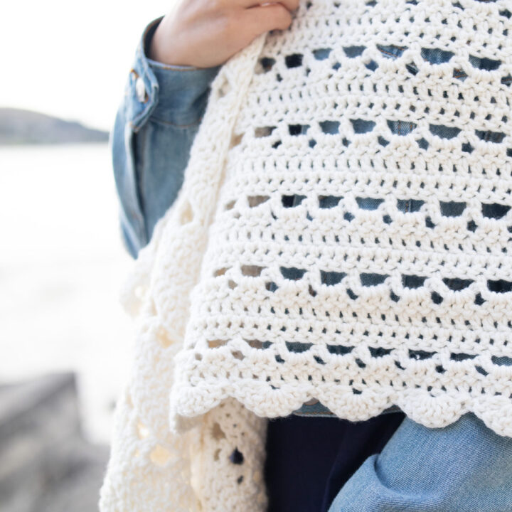 close up on scallop mesh crochet stitches on a cream triangle wrap shawl