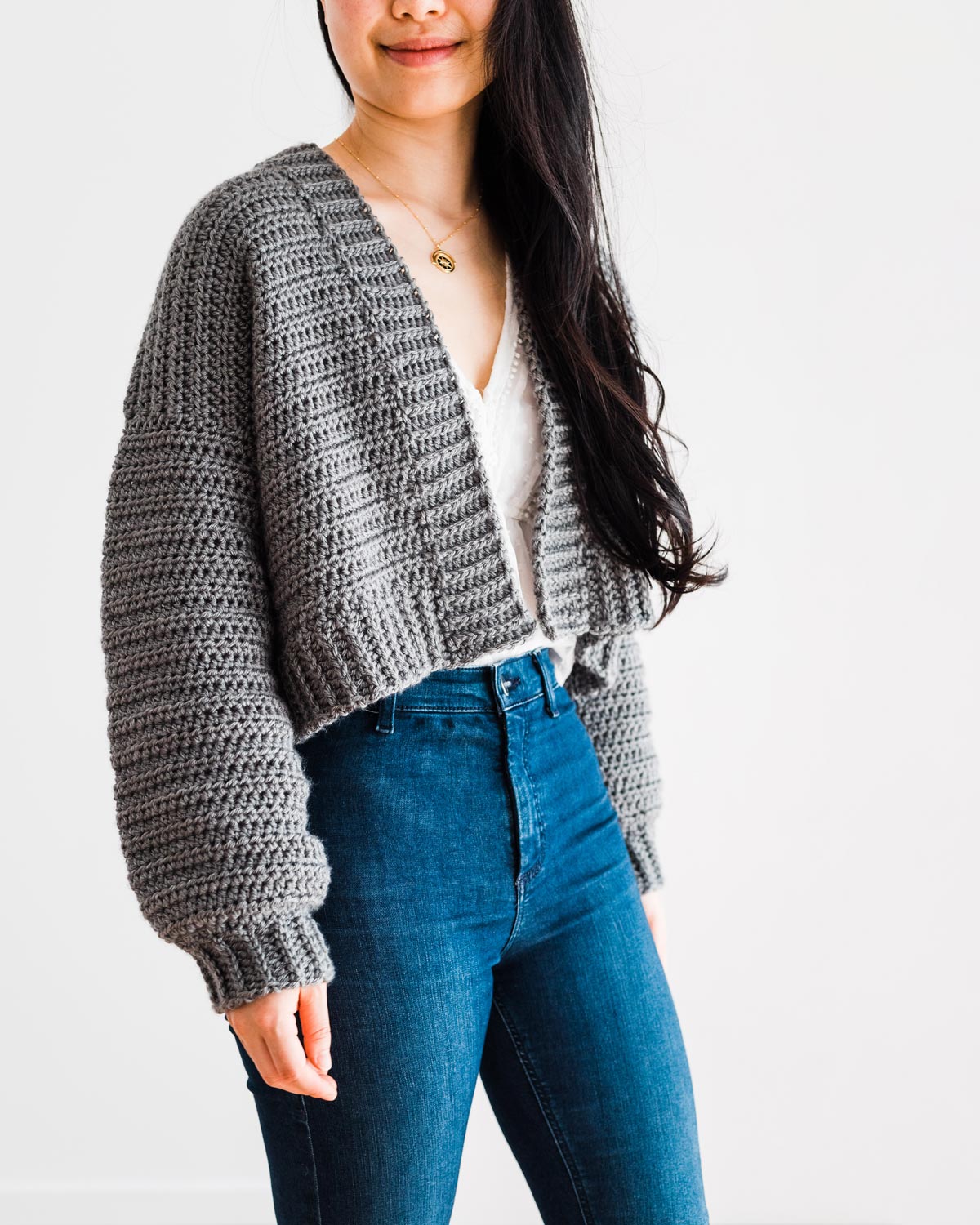 woman wearing grey crop crochet sweater with chunky neck and hem ribbing